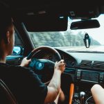 man in black tank top driving car
